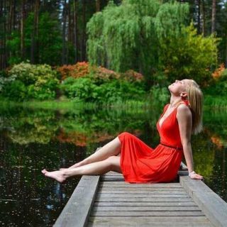 Žena v červených šatek na břehu rybníka